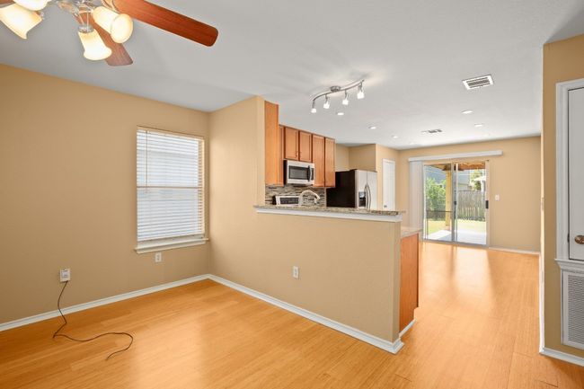 Kitchen featuring appliances with stainless steel finishes, light wood-style flooring, decorative backsplash, a peninsula, and a ceiling fan | Image 6