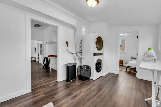 Washroom featuring stacked washer / drying machine, dark wood-style floors, and baseboards | Image 13