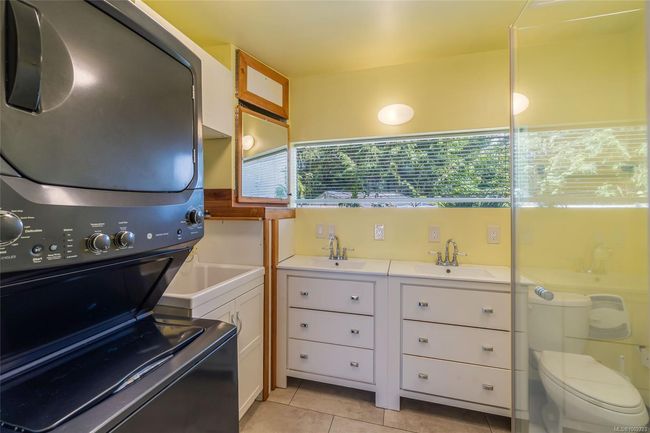 Full bath featuring stacked washer / dryer, tile patterned floors, double vanity, and toilet | Image 41
