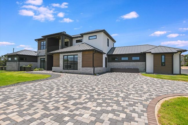 Modern home with a standing seam metal roof, decorative paver driveway, and brick siding | Image 7