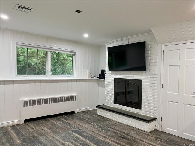 Unfurnished living room featuring dark hardwood / wood-style flooring, a brick fireplace, and radiator | Image 8