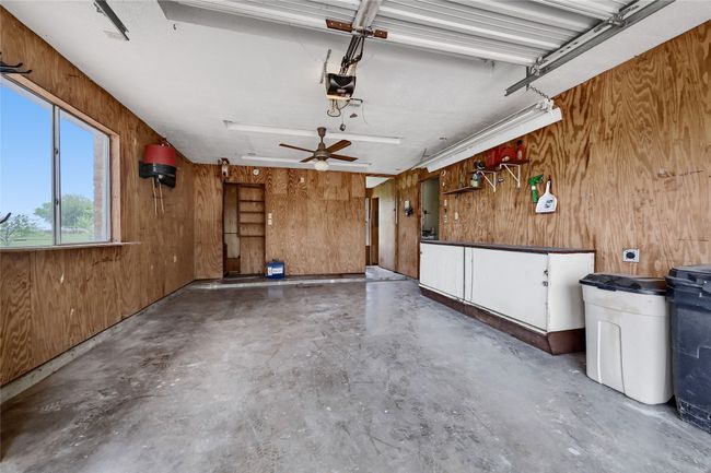 Garage featuring wood walls, a garage door opener, and ceiling fan | Image 36
