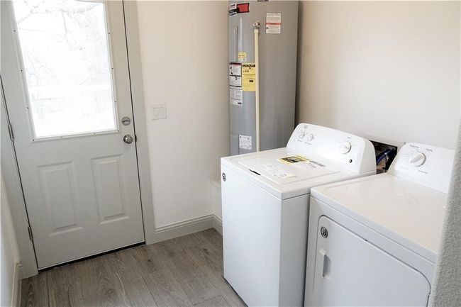 Laundry area with water heater, washing machine and clothes dryer, light wood-type flooring, and baseboards | Image 16