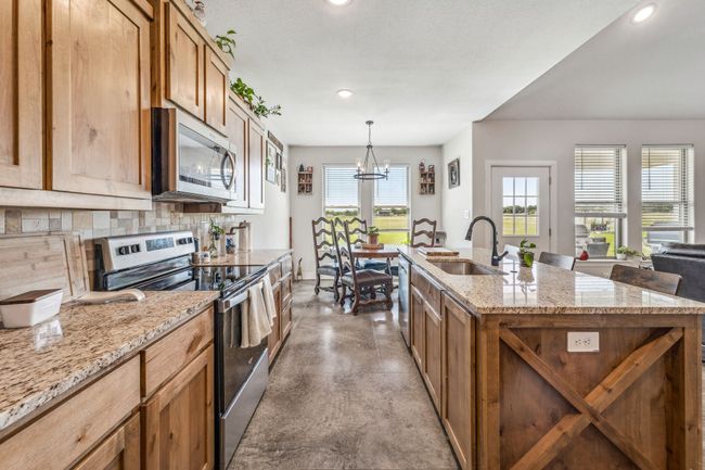 Kitchen featuring stainless steel appliances, a sink, concrete floors, backsplash, and a chandelier | Image 9