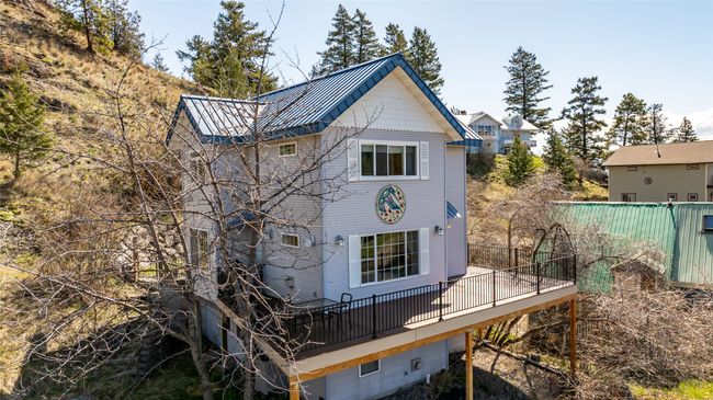 Back of house with a deck, metal roof, and fence | Image 49