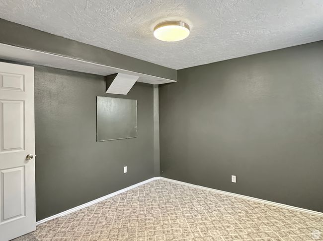 Finished basement featuring a textured ceiling, baseboards, and carpet | Image 24