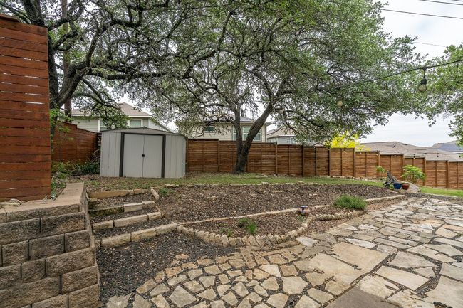 Fenced in yard with garden beds, landscaping and shed. | Image 33