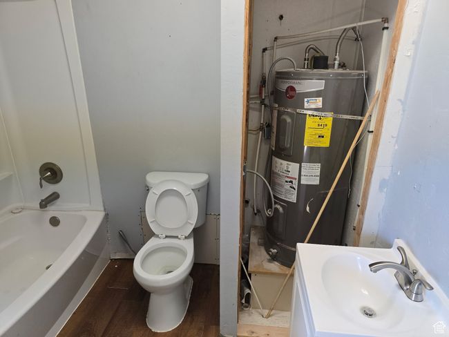 Bathroom with water heater, wood finished floors, toilet, and a sink | Image 7