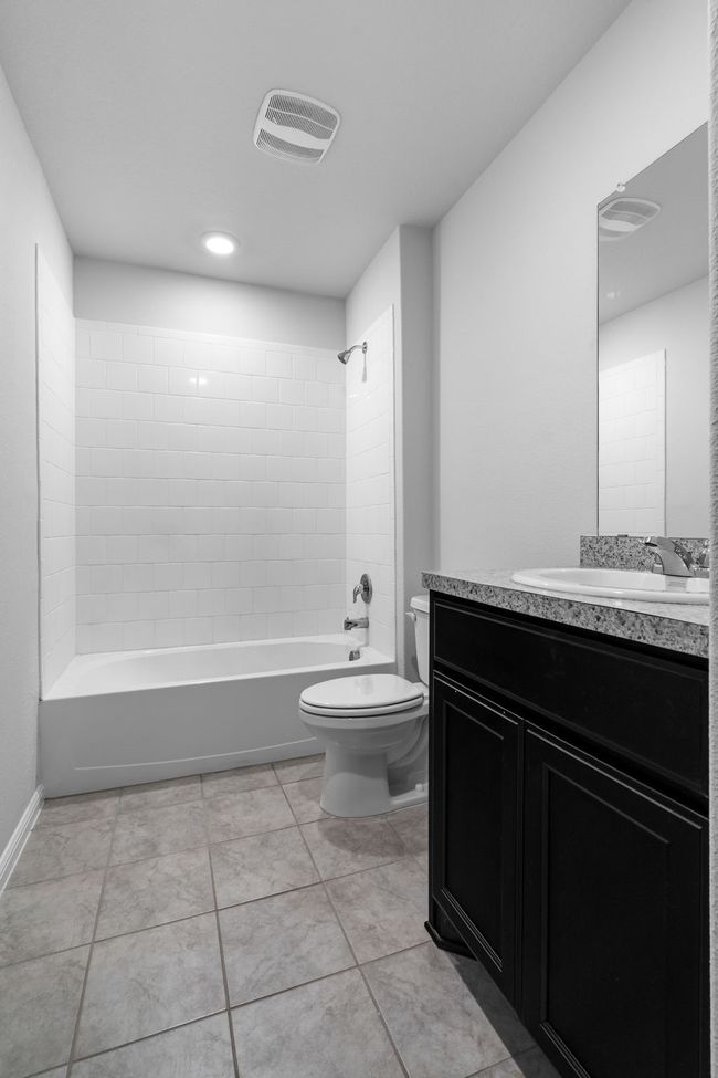 Full bathroom featuring bathtub / shower combination, tile patterned floors, toilet, vanity, and visible vents | Image 20