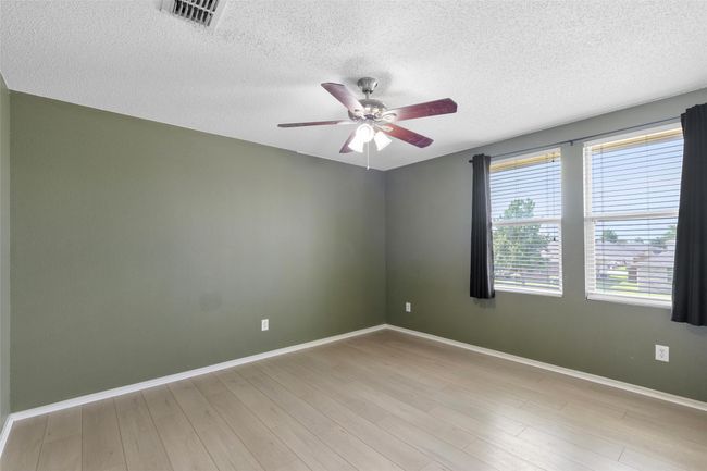 Empty room with a ceiling fan, a textured ceiling, and light wood-style flooring | Image 21
