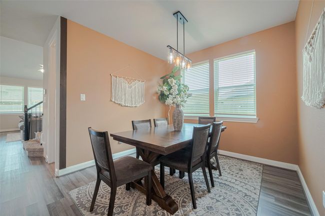 This dining area features warm peach walls, a modern light fixture, and large windows for natural light creating a cozy and inviting atmosphere. | Image 20