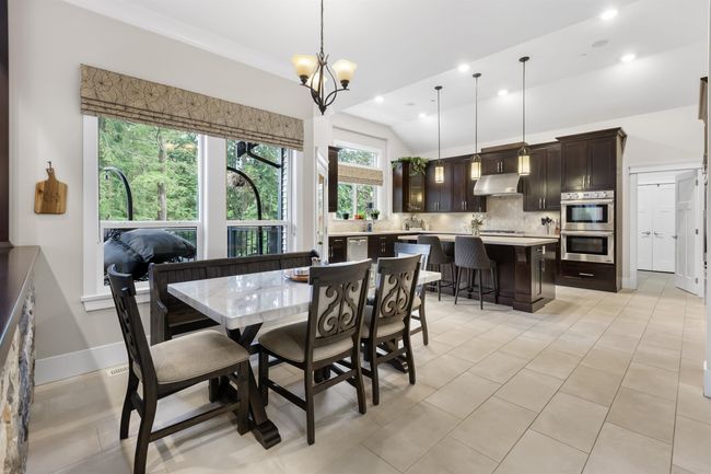 Dining area featuring light tile patterned floors, lofted ceiling, recessed lighting, a chandelier, and baseboards | Image 10