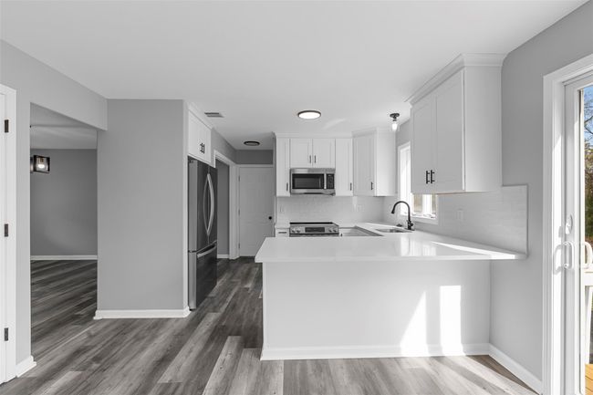 Kitchen with appliances with stainless steel finishes, light countertops, a sink, baseboards, and a peninsula | Image 4