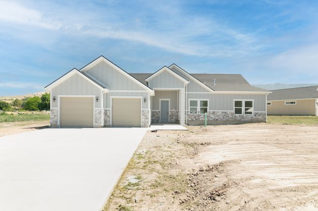 View of front facade featuring an attached garage, stone siding, concrete driveway, board and batten siding, and a shingled roof | Image 25