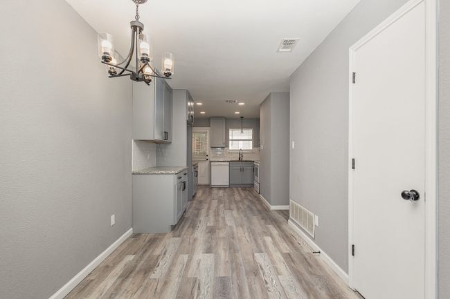 Hallway featuring light wood-type flooring, a chandelier, a sink, baseboards, and recessed lighting | Image 13