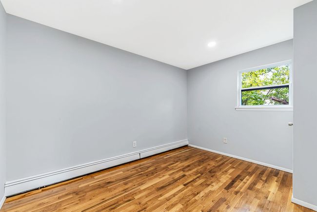Spare room featuring a baseboard radiator, wood finished floors, and baseboards | Image 14