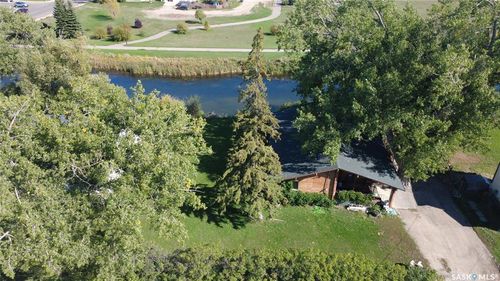 Waterfront property featuring a private driveway, mature trees, and a green lawn | Card Image