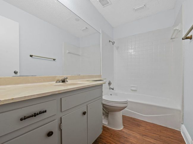 Bathroom featuring wood finished floors, shower / tub combination, vanity, and a textured ceiling | Image 16