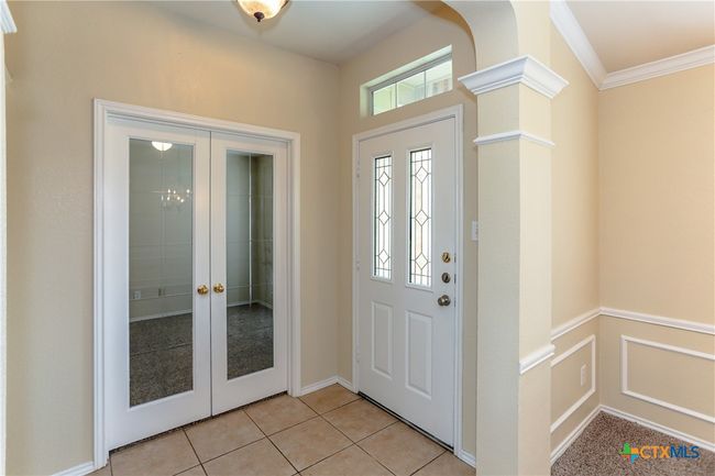 Front door and entry way looking into the first bedroom with French doors. | Image 9
