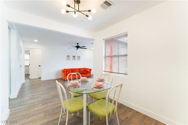 Dining room with light wood finished floors, baseboards, visible vents, and a chandelier | Image 11