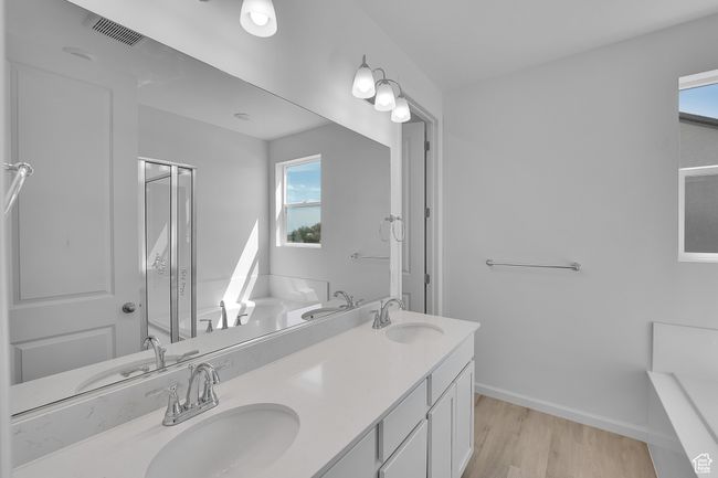 Full bath featuring double vanity, wood finished floors, healthy amount of natural light, and a bathtub | Image 5