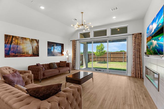 Living room with a chandelier, wood finished floors, lofted ceiling, a fireplace, and recessed lighting | Image 13