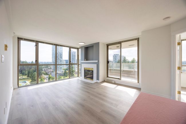 Unfurnished living room with plenty of natural light, expansive windows, a tile fireplace, and wood finished floors | Image 8