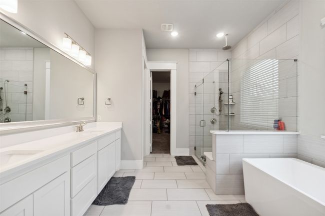 Bathroom featuring a stall shower, double vanity, a soaking tub, a spacious closet, and tile patterned flooring | Image 19