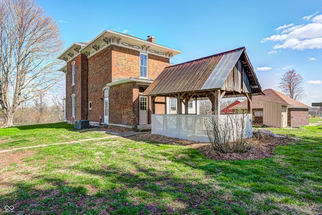rear view of property featuring cooling unit, a yard, a chimney, and brick siding | Image 4