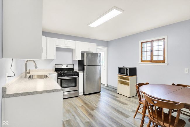 kitchen featuring a sink, stainless steel appliances, light countertops, white cabinets, and light wood finished floors | Image 6