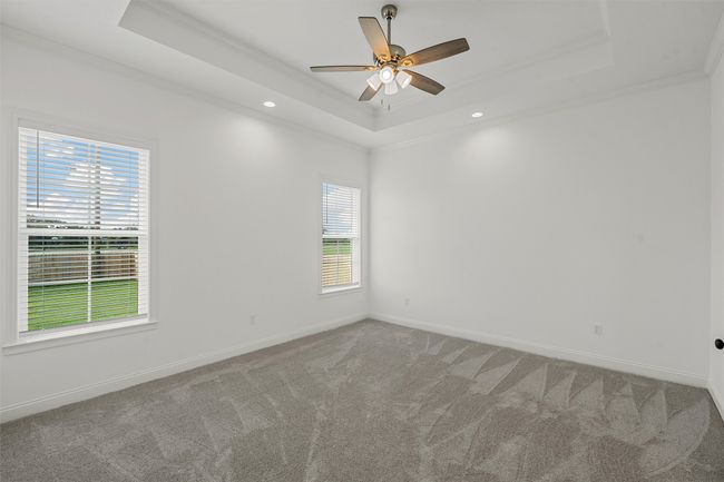 Carpeted empty room featuring a tray ceiling, crown molding, recessed lighting, and ceiling fan | Image 27