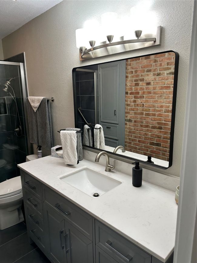 Full bath featuring a textured wall, a stall shower, vanity, toilet, and a textured ceiling | Image 17