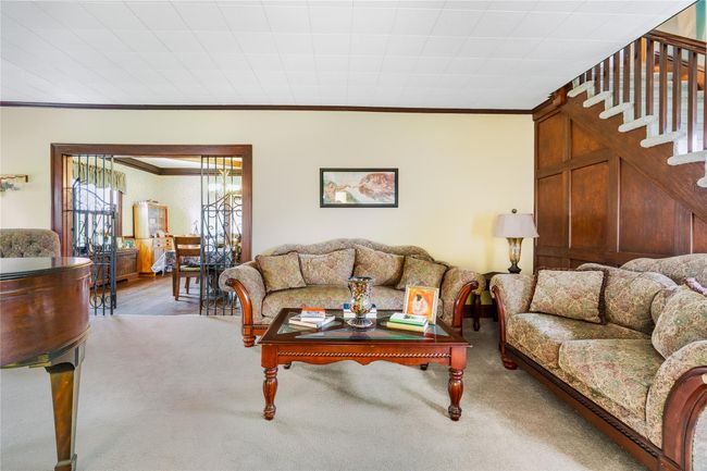 Carpeted living room featuring stairway and crown molding | Image 5