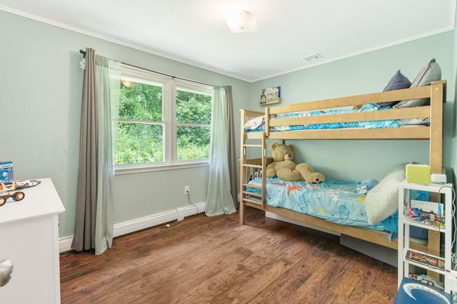 Bedroom with ornamental molding, wood finished floors, a baseboard radiator, and baseboards | Image 28