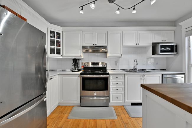Kitchen featuring a sink, appliances with stainless steel finishes, white cabinetry, and under cabinet range hood | Image 15