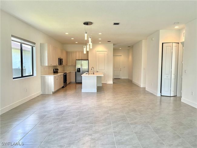 Kitchen with light tile patterned floors, stainless steel appliances, an island with sink, sink, and hanging light fixtures | Image 17