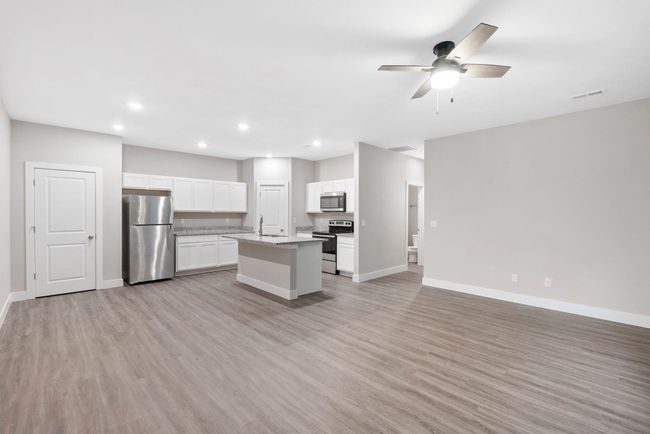 Kitchen featuring appliances with stainless steel finishes, open floor plan, baseboards, a kitchen island with sink, and recessed lighting | Image 7