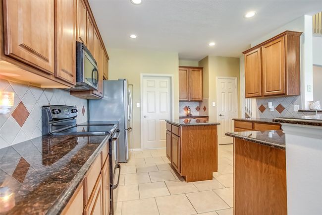 Kitchen with stainless steel electric range oven, lots of cabinetry, a center island, recessed lighting, and tasteful backsplash. | Image 12