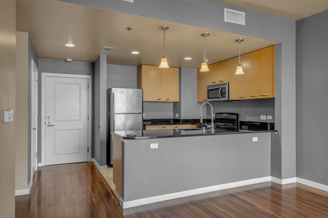 Kitchen with a peninsula, dark countertops, visible vents, and stainless steel appliances | Image 4