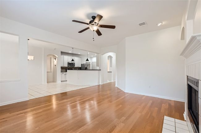 Unfurnished living room with arched walkways, a ceiling fan, light wood-style flooring, and baseboards | Image 15