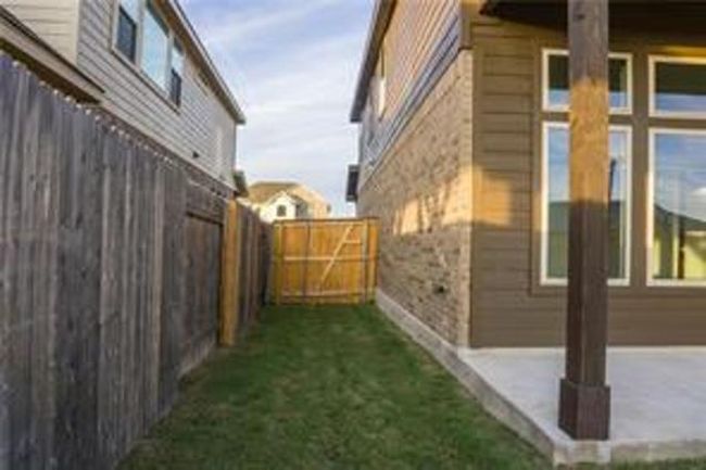 View of home's exterior featuring a fenced backyard, stone siding, and a patio area | Image 23