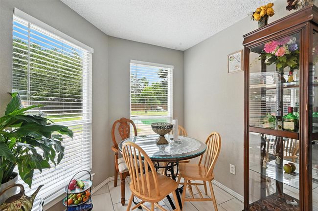 Dining room with healthy amount of natural light, light tile patterned flooring, and a textured ceiling | Image 12