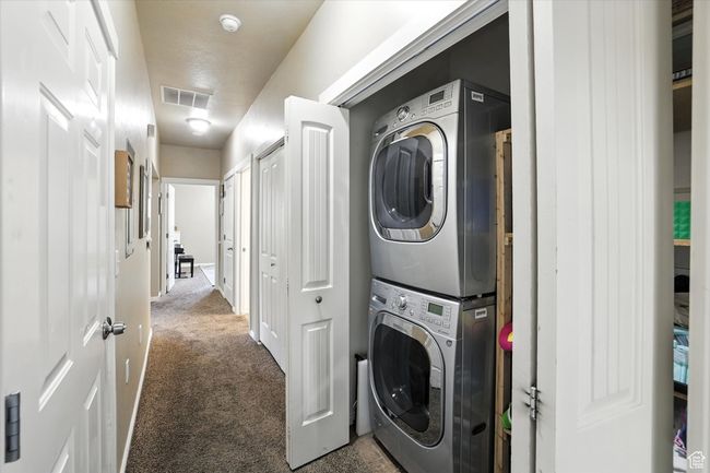 Laundry area with stacked washer / drying machine and carpet floors | Image 21