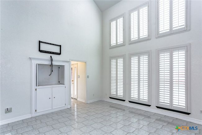 Family room with built in entertainment area and natural light. Wooden shutters on the windows. | Image 16
