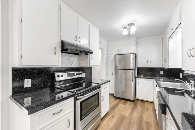 Kitchen with appliances with stainless steel finishes, under cabinet range hood, backsplash, and white cabinetry | Image 21
