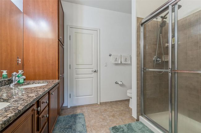 Bathroom featuring a sink, tile patterned floors, toilet, and a shower stall | Image 11