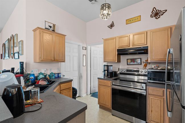 Kitchen featuring stainless steel appliances, under cabinet range hood, dark countertops, and light brown cabinets | Image 11