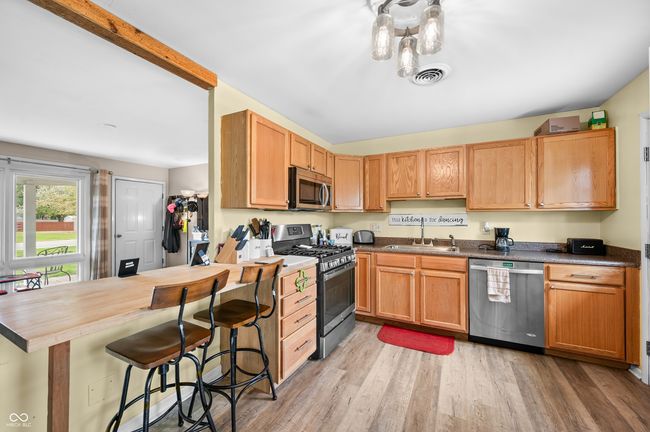 kitchen with stainless steel appliances, a sink, visible vents, light wood-style floors, and a breakfast bar area | Image 20