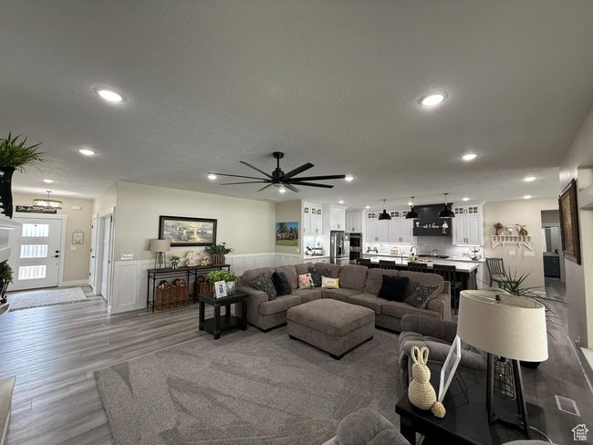 Living area with recessed lighting, ceiling fan with notable chandelier, a textured ceiling, a wainscoted wall, and wood finished floors | Image 15