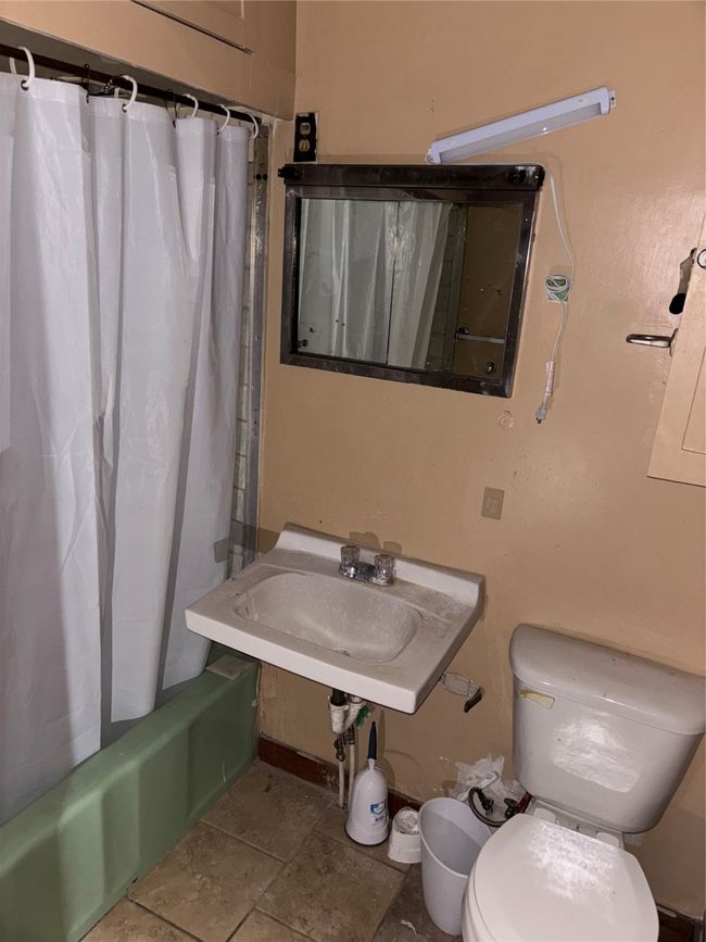 Bathroom featuring toilet, shower / bath combo with shower curtain, and a sink | Image 7
